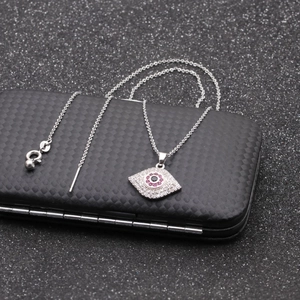 Macro della collana con ciondolo occhio del diavolo e zirconi rosa su scatola nera