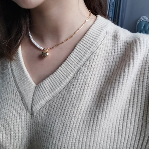 Asymmetric heart pendant necklace with pearls and golden paperclip chain on a model