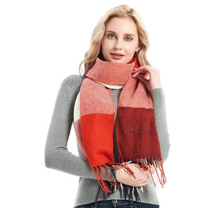 Nahaufnahme eines weichen Karo-Schals mit Quasten in Rot-Blau über grauem Pullover