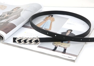 Détail d'une ceinture élastique noire avec boucle chaîne argentée et trous de réglage