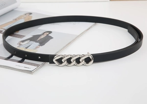 Détail d'une fine ceinture élastique noire avec boucle en métal argenté sur un magazine