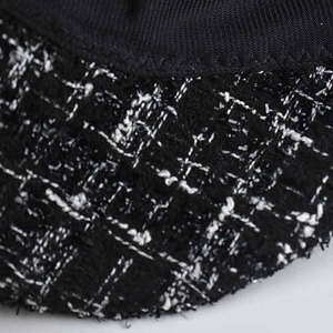 Detailed macro view of black and white checkered tweed fabric and fine edge stitching
