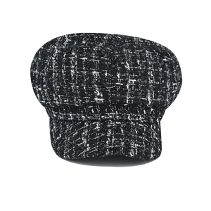 Detailed view of black and white tweed newsboy cap with classic textured pattern weave