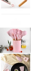 Dettaglio del set di utensili da cucina in silicone rosa con manici in legno e secchiello