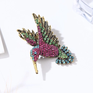 Macro detail of vintage gold hummingbird brooch featuring vibrant multicolored rhinestones