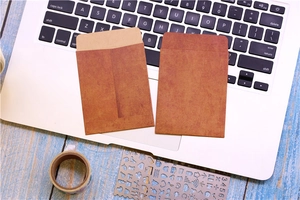 Close-up of vintage brown kraft paper envelopes on a laptop and blue wooden desk