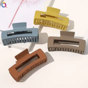Close-up of four matte rectangle hair claws in mustard, blue, and brown earth tones