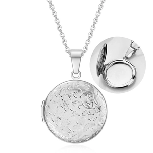 Macro shot of silver photo locket necklace with vintage floral engraving and open design