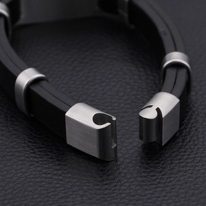 Black silicone bracelet with brushed stainless steel clasp on leather background