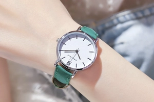 Nahaufnahme einer Damenuhr mit weißem römischem Zifferblatt und grünem Lederarmband