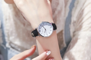 Detailaufnahme einer minimalistischen Damenquarzuhr mit weißem Zifferblatt und Lederarmband