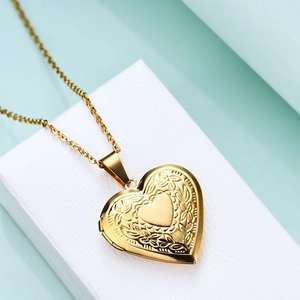 Macro view of a gold heart locket necklace with vintage floral relief and smooth center