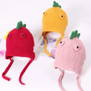Detail of knitted baby hats with cartoon eyes and dinosaur spikes in red, yellow and pink