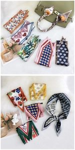 Flat lay of narrow silk scarves with various patterns on white fur and bag accessory