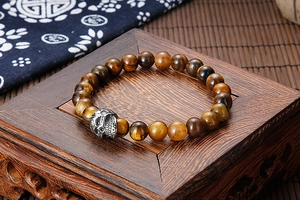 Detailed view of tiger eye stone beads and vintage steel skull on a wood stand