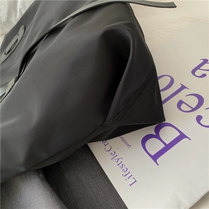 Close-up of black nylon tote bag showing detailed stitching and durable fabric texture