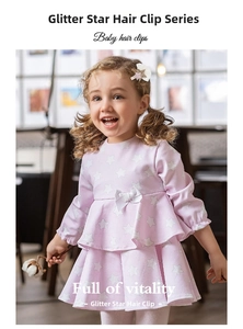 Detail of glitter star hair clip with white lace trim worn by child on pink dress
