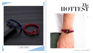 Detail showing navy and red braided rope bracelets with black metal horseshoe shackles