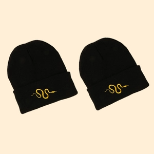 Two black knitted beanies featuring gold snake embroidery on folded cuffs for autumn warmth