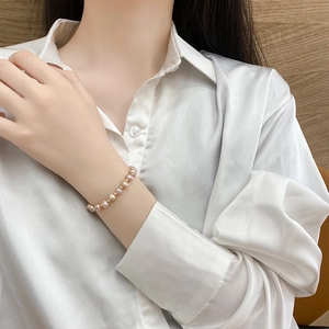 Detail of 14K gold plated bracelet with natural pink baroque pearls on model's wrist