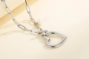 Détail du collier chaîne trombone argentée avec pendentif cœur, perle et fermoir OT