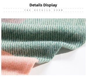 Close-up detail of soft knitted neck warmer fabric with teal and pink diagonal weave patterns