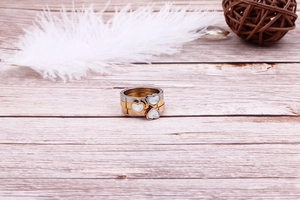 Three-piece heart ring set in silver, gold, and rose gold with shell inlay on wood surface
