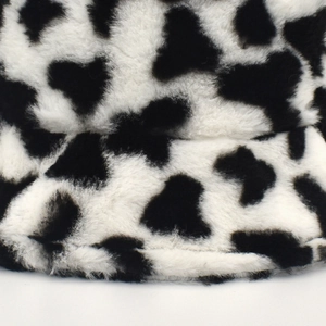 Close-up of fluffy black and white cow print faux fur texture on a plush bucket hat