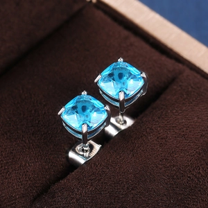 Macro detail of square-cut light blue zircon earrings in a classic four-prong silver setting