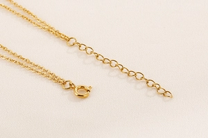Detailed macro view of gold-plated 18K stainless steel extender chain and spring clasp