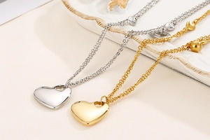 Flat lay view of 18K gold and silver stainless steel heart pendant necklaces set