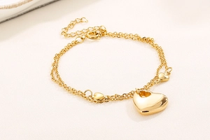 Detail of 18K gold plated double-layer bracelet featuring three heart charms on fabric