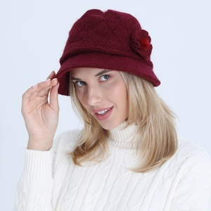 Detail of burgundy knitted bucket hat with flower accent on model in winter setting