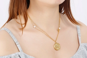 Close-up of a double-layer gold necklace with a Tree of Life pendant and pearl detail