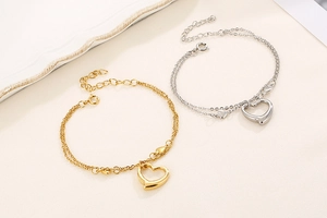 Detail of gold and silver heart pendants on double-layered stainless steel chain bracelets