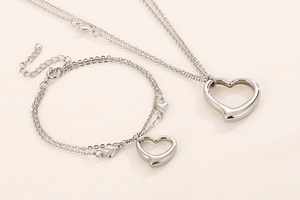 Detail showing silver heart pendant necklace and bracelet set with layered steel chains