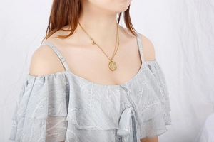 Détail d'un collier doré double couche avec pendentif rond porté par un mannequin