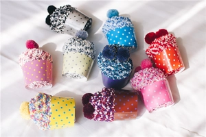 Detailed view of colorful cupcake-shaped coral fleece socks with decorative pom-poms