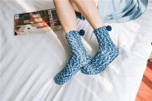 Close-up of thick coral fleece socks in blue and white knit with pom-pom detail