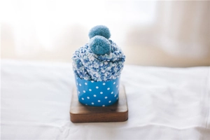 Detailed texture of blue coral fleece cake socks with soft pompoms in cupcake paper