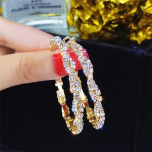 Macro shot of gold-plated twisted hoop earrings with sparkling cubic zirconia inlay
