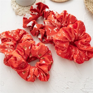 Close-up of three red velvet Christmas scrunchies with white stars and snowflake patterns