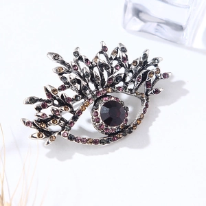 Vintage eye-shaped silver brooch with a purple gemstone and amber crystal accents