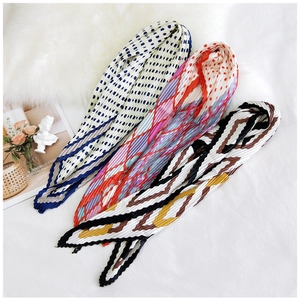 Detailed view of pleated neck scarves in polka dot and floral patterns on a plush mat