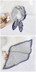 Detail of pleated silk scarf with blue polka dots on white background and brown border