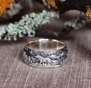 Close-up of vintage silver wolf ring with detailed forest embossing on rustic wood
