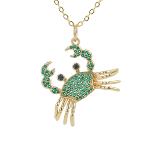 Detailed close-up of crab pendant necklace with green and black crystals in gold finish