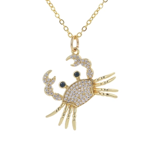 Macro shot of gold crab necklace featuring sparkling white zircon pavé and black gem eyes
