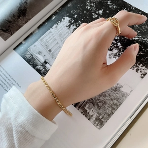 Detail of twisted rope chain bracelet and anchor link ring on a model's hand