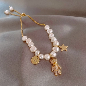 Detail of baroque pearl bracelet with gold teddy bear and engraved LOVE charm